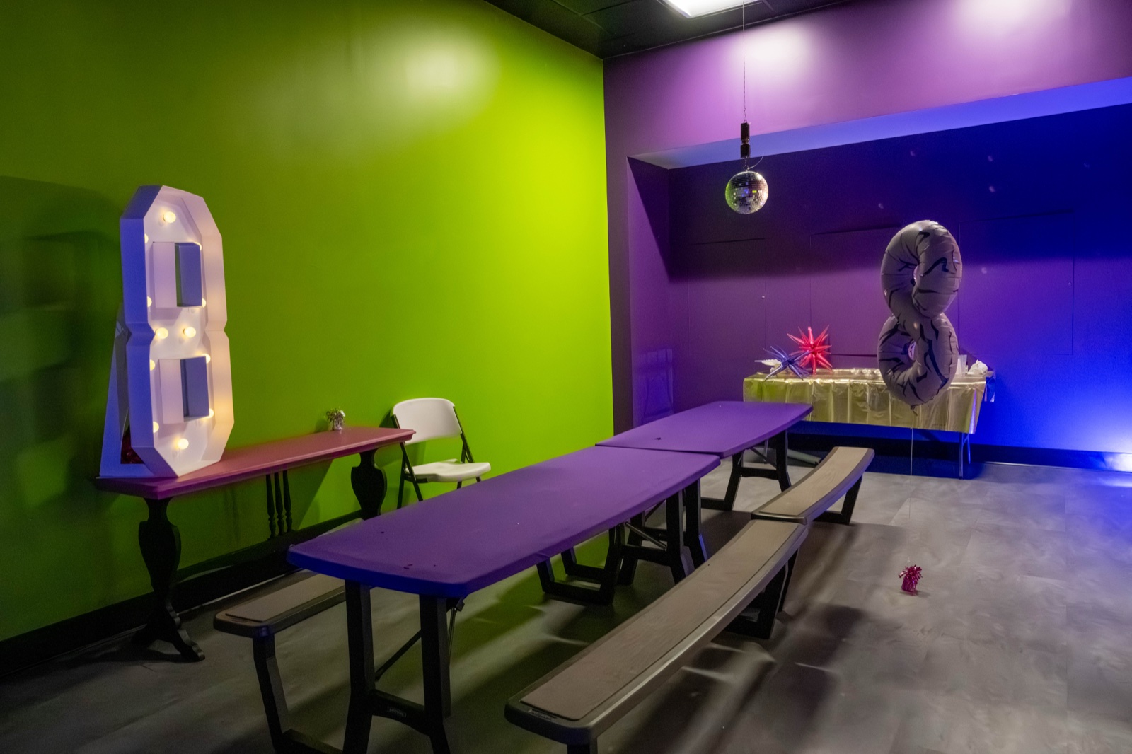 The Blast'D! birthday party room with a light-up number 8, foil balloons, a disco ball and purple tables